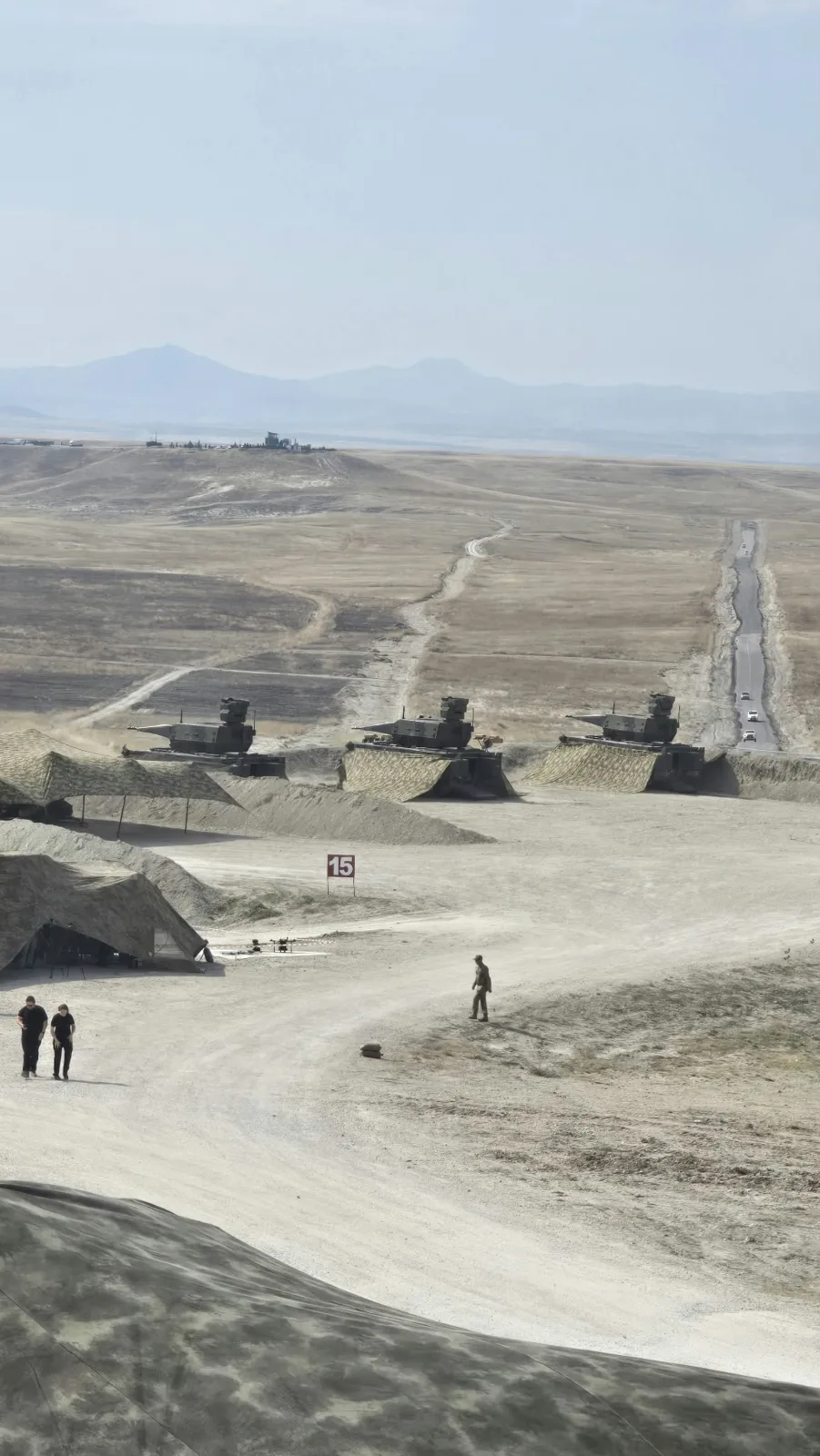 Emplaced vehicles behind earth berms on the firing line, seen from above. Photo: Envanter Medya